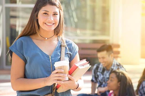 Smiling student holding books and coffee